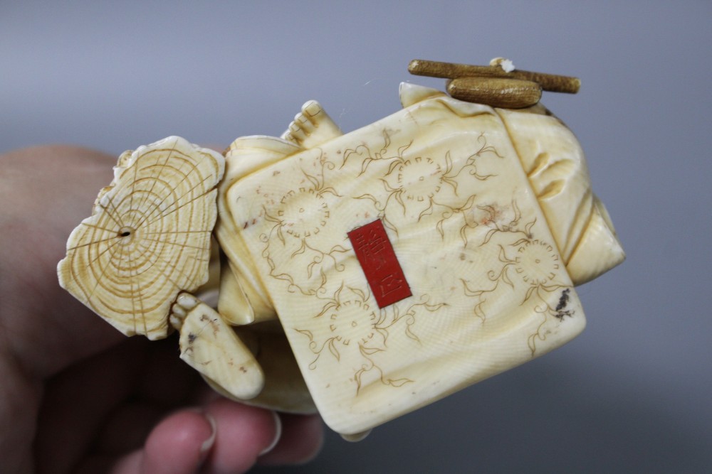 A Japanese Meiji period ivory okimono carved with a doctor treating a mans ear, signed, height 12cm